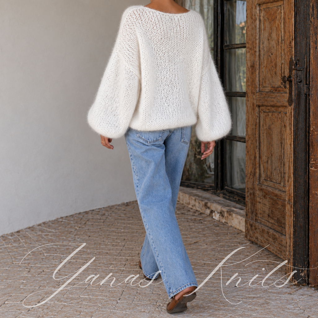 Full back view of an ivory loose knit pullover with balloon sleeves worn with jeans