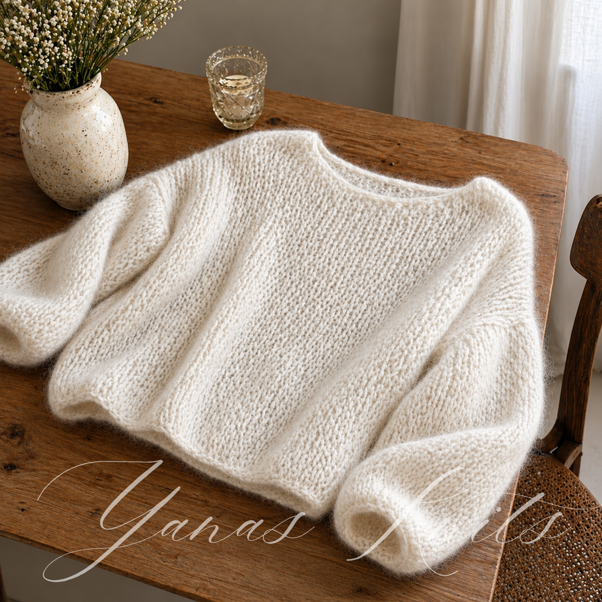 Ivory oversized boat neck sweater laid on a wooden table with its knitted texture and balloon sleeves visible