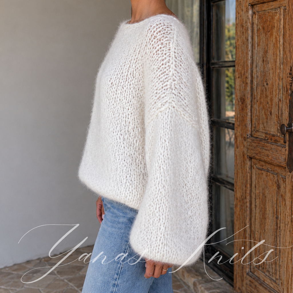 Side view of a fluffy ivory pullover showing the wide neckline and voluminous long sleeves